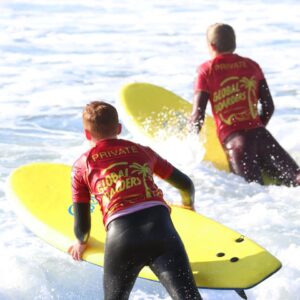 Children entering the sea with surfboards on a rainy day in Cornwall